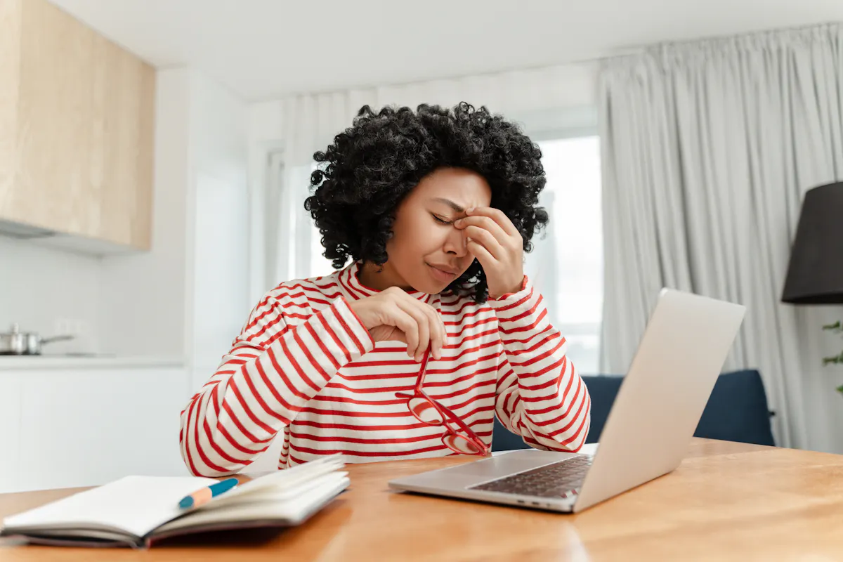 Black woman in red white sweater holding red glassess stressed