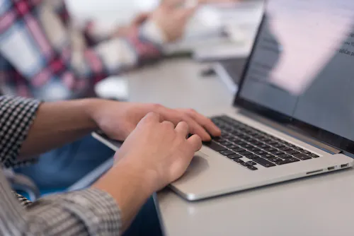 Hands typing on laptop