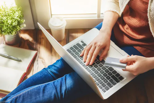 Holding credit card while shopping on laptop