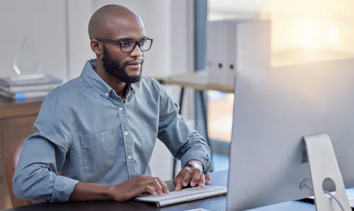 Man in glasses staring intently as screen