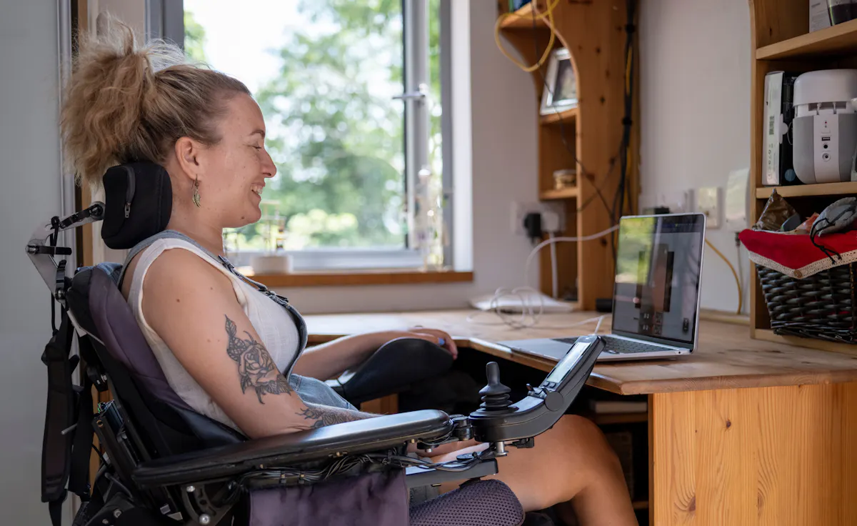 Woman in electric wheelchair having video call on laptop