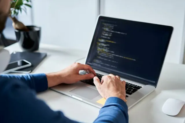 A coder typing on a laptop.