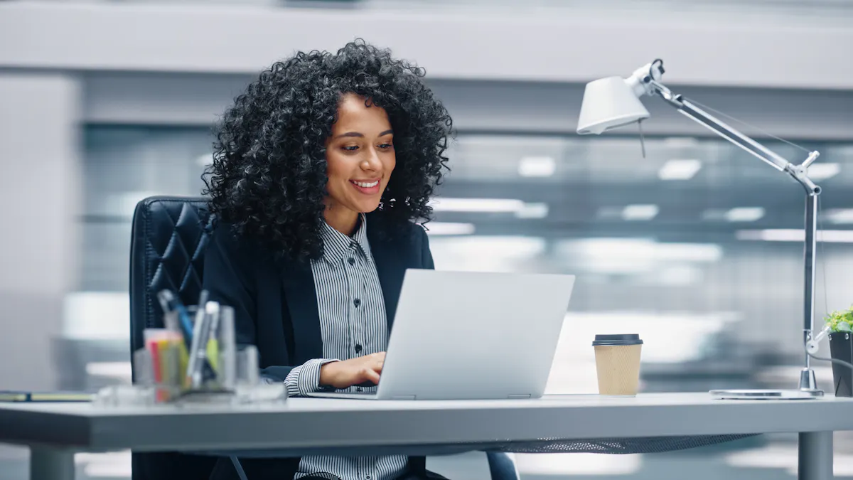 A smiling office worker works on a laptop.