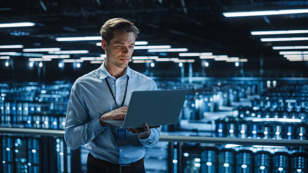 A cybersecurity professional consults a laptop while standing in a data center.