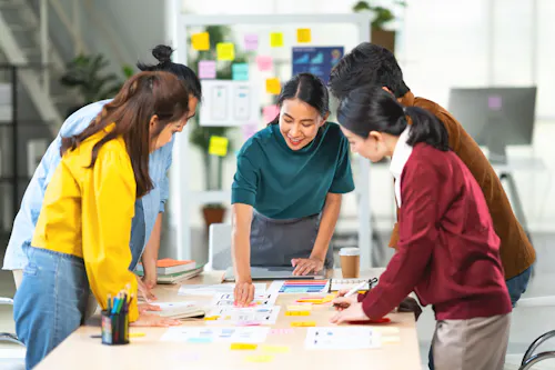 A product manager meets at an office work table with team members designing a mobile app.