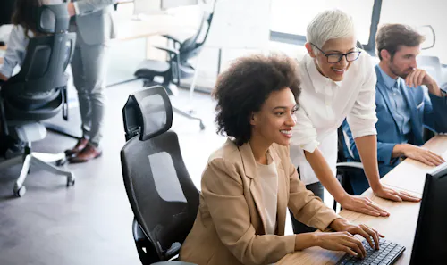 A product manager and software engineer review a software product on a monitor.