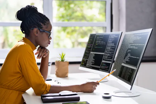 A software engineer reviews code on a monitor.