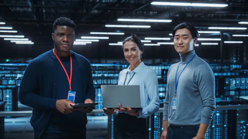 A team of three information security professionals work on computer devices in a server room.