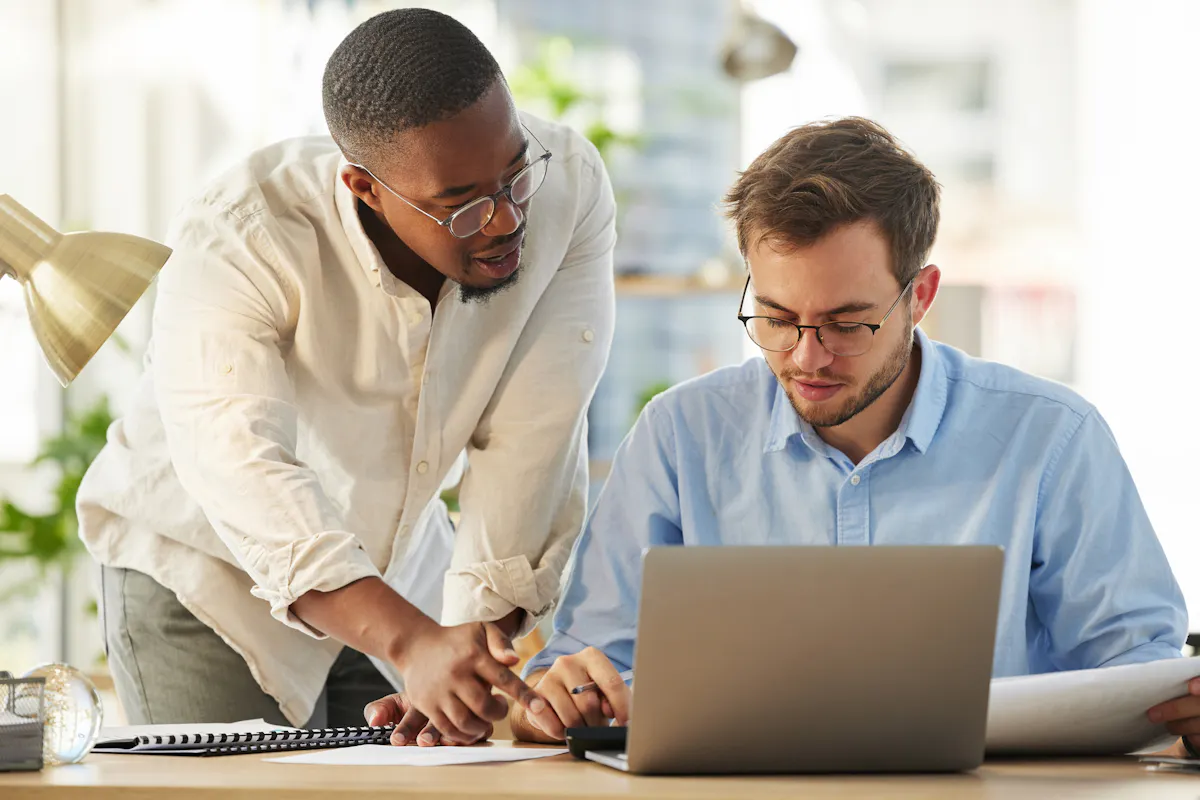 Two cybersecurity professionals looking at a penetration testing project on a laptop.