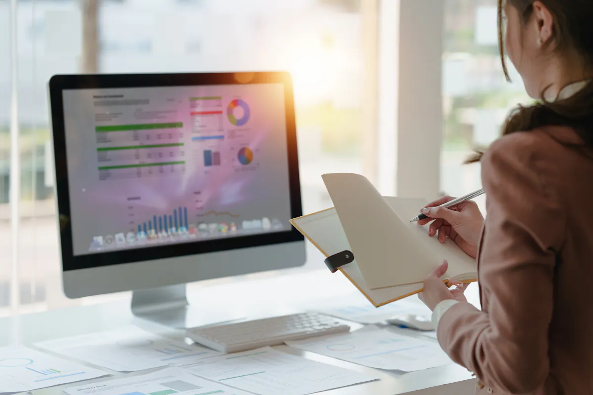 A data analyst creates a data visualization dashboard on a monitor.