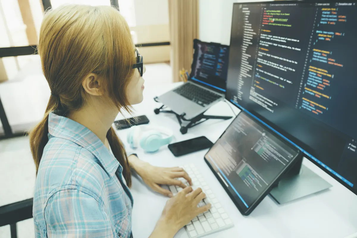 A computer programmer reviews code on a monitor.