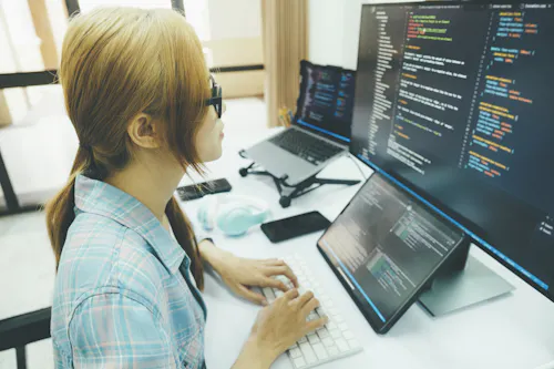 A computer programmer reviews code on a monitor.