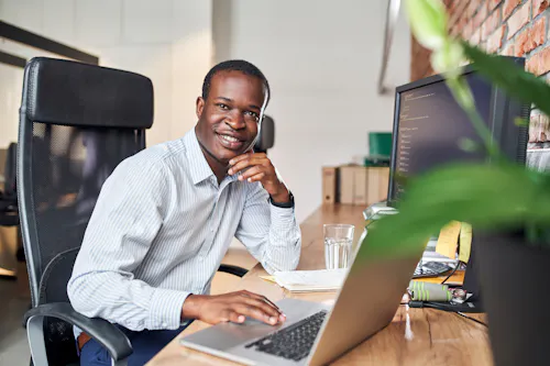 Smiling data scientist works at a computer in an office.