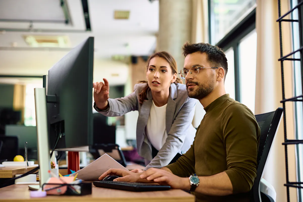 Two AI and machine learning professionals look at a computer screen.