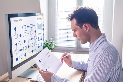 A database administrator works on a flowchart using a monitor.