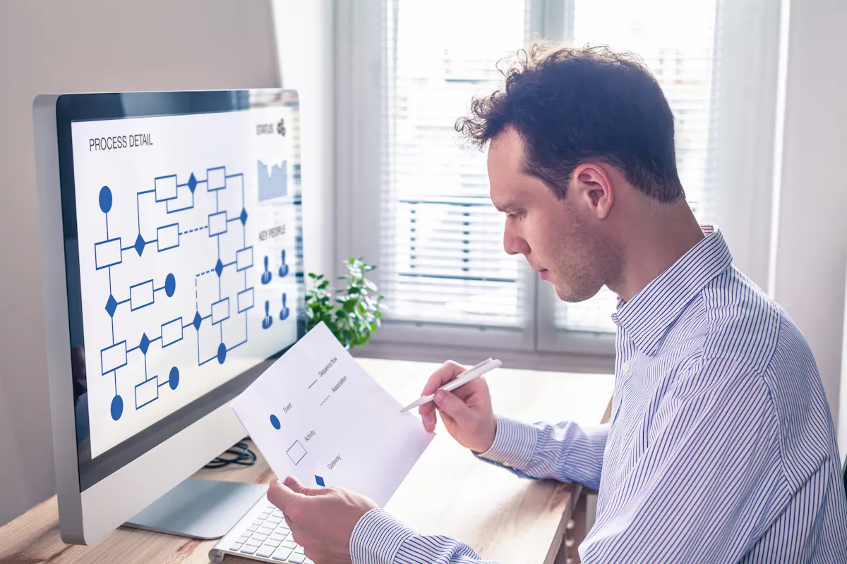 A database administrator works on a flowchart using a monitor.