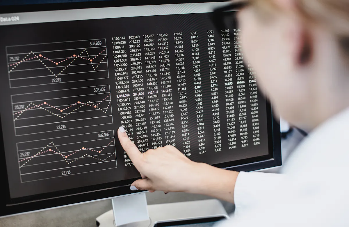 A data scientist points at a graph on a computer screen.