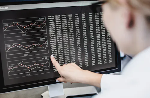 A data scientist points at a graph on a computer screen.