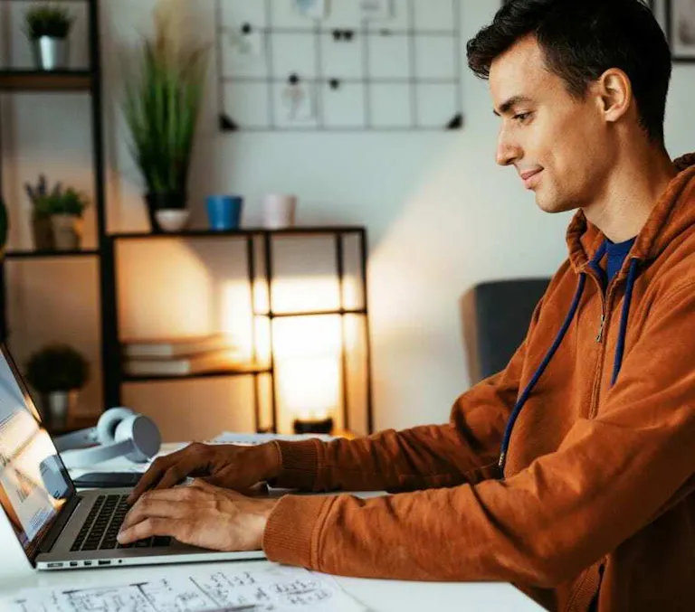 Man orange hoodie working at laptop