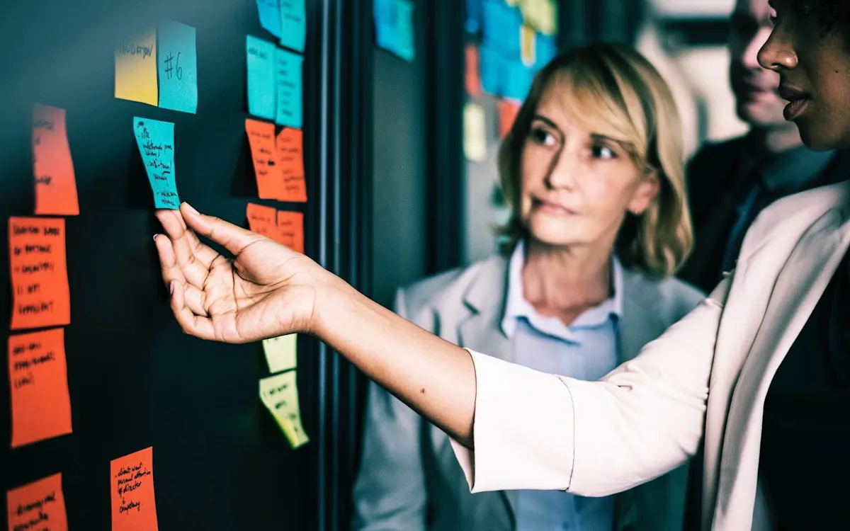 Older woman looks at younger colleague holding post it