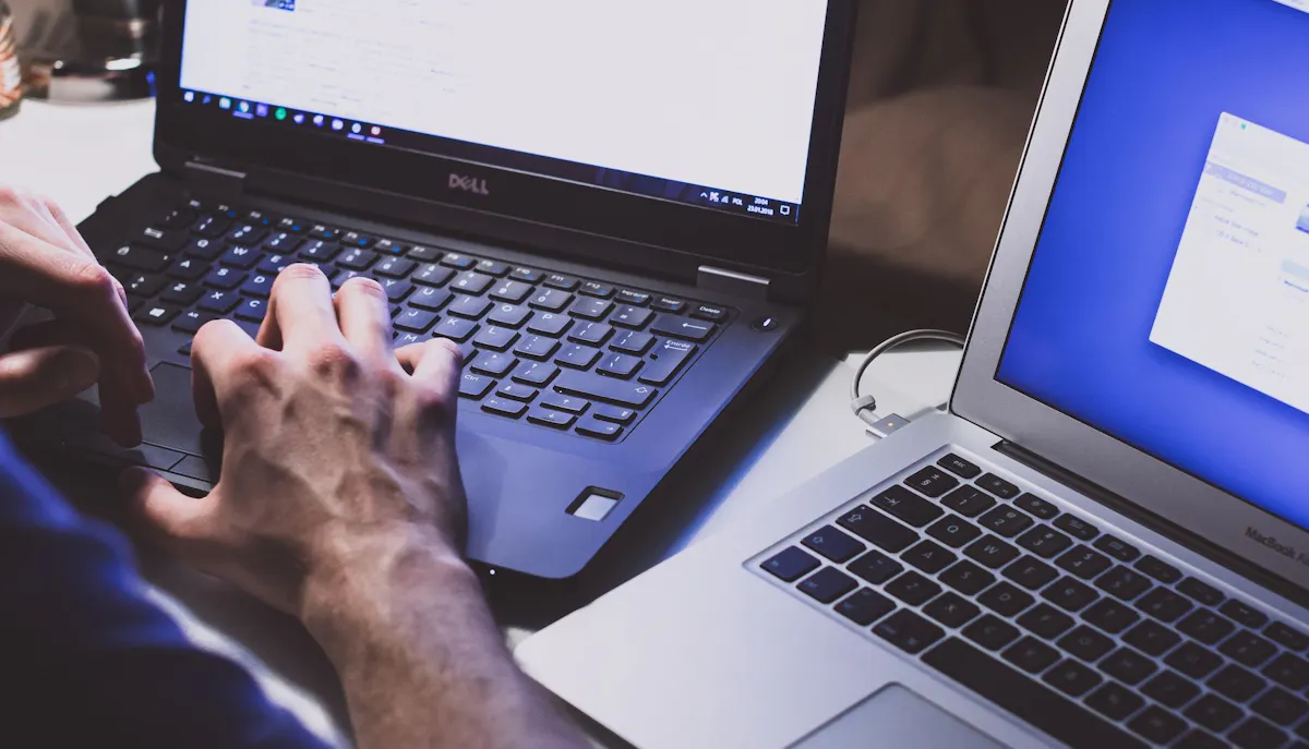 Two open laptops with a hand typing on dell