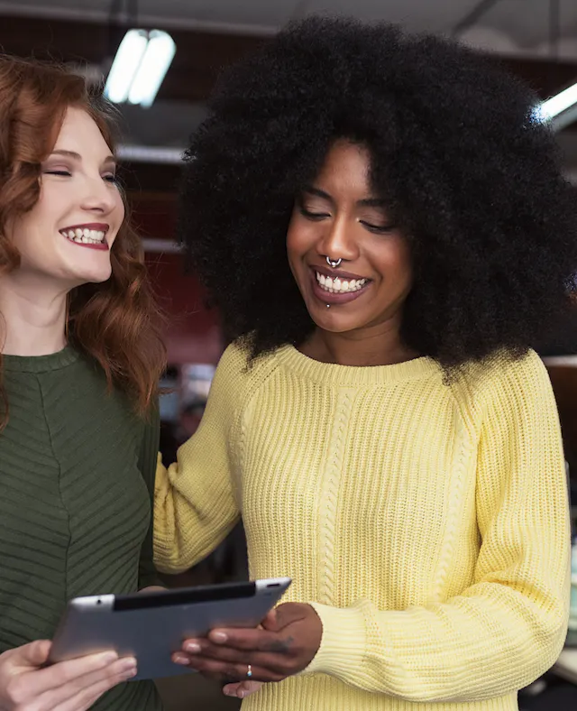 Two women laughing over ipad