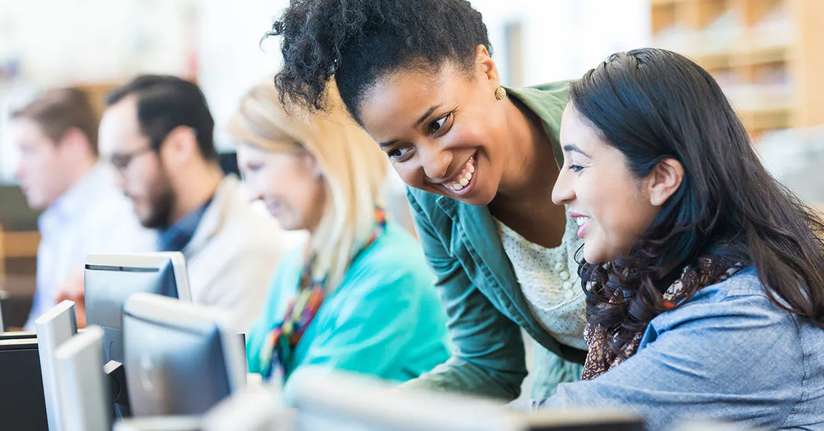 Women smiling toward computers wide